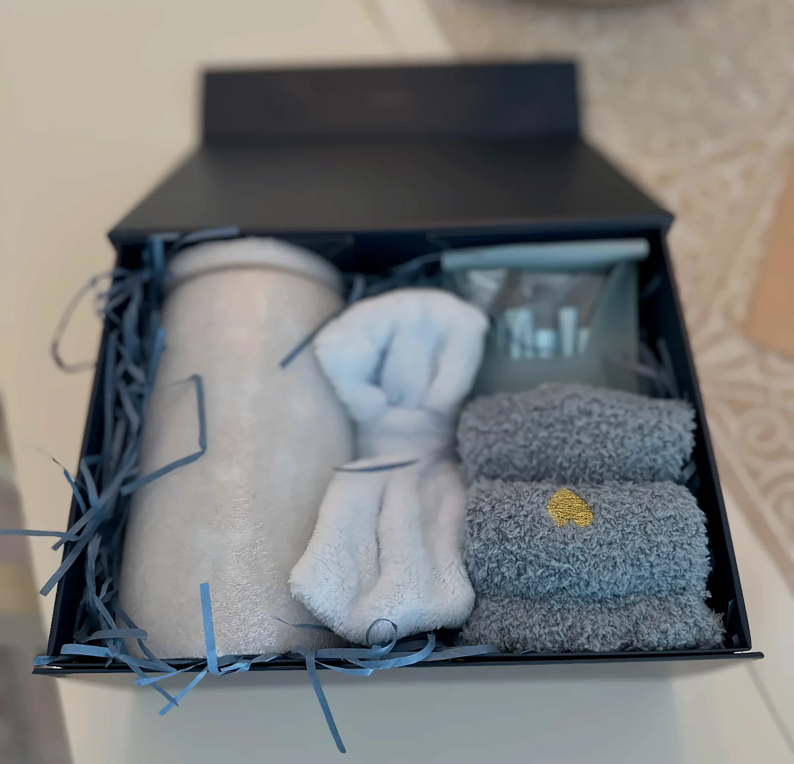 A navy employee gift box open on a table, set in blue paper shred
