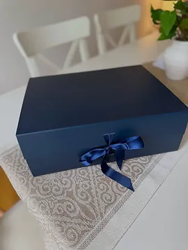 The navy box closed, with a navy satin bow tied at the front