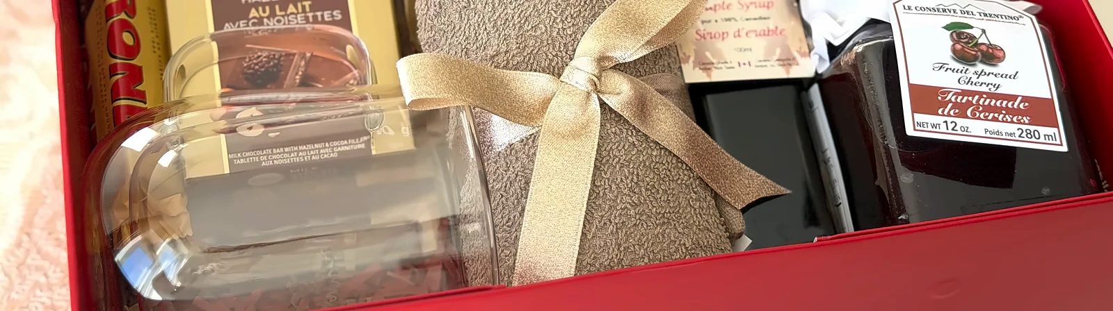 The inside of the red box along the front, a gold ribbon tied round one of the gifts