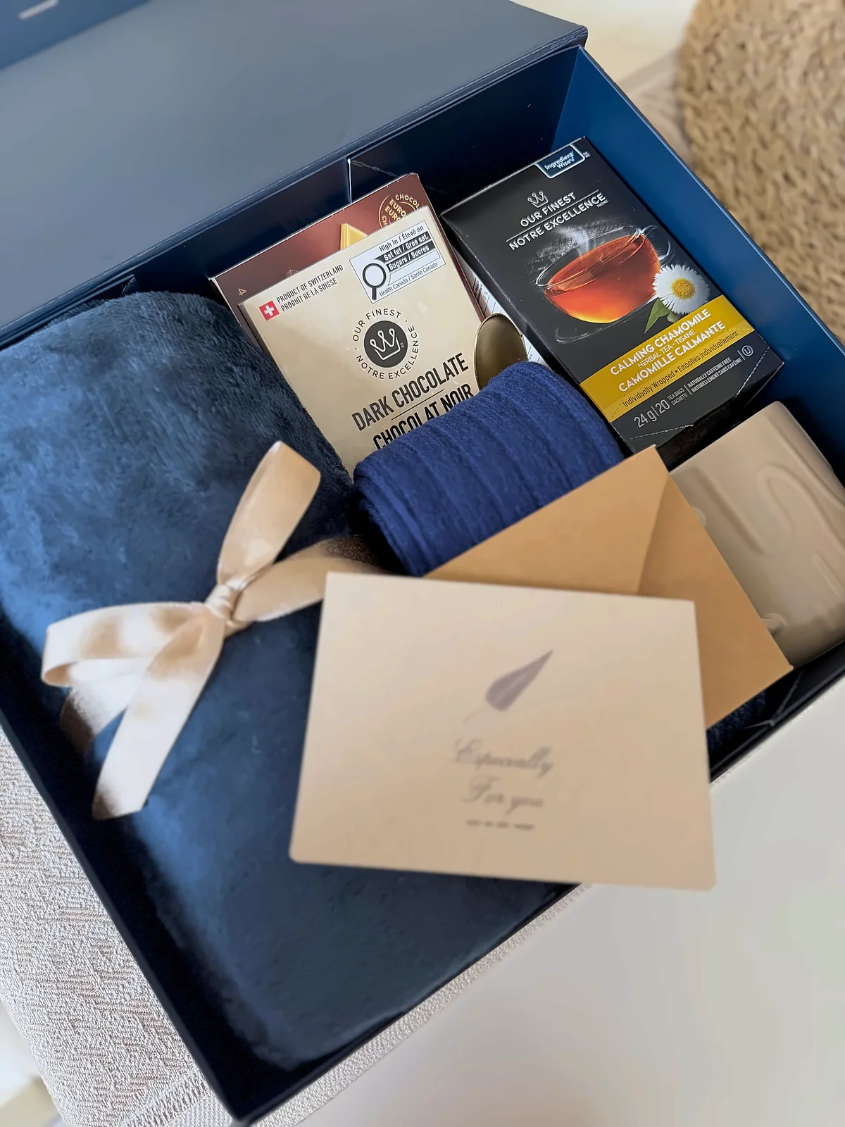 A navy gift box open, with a card resting on top